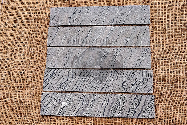 May include: Five pieces of black and white patterned wood, arranged in a row on a brown burlap background. The wood has a wavy, marbled pattern.