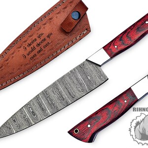 May include: A Damascus steel chef's knife with a red wood handle and a leather sheath. The sheath is engraved with the text "I choose you, I would choose you over and over..."