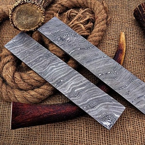 May include: Two long, rectangular pieces of metal with a wavy, patterned surface. The metal is a light gray color. The pieces are lying on a brown burlap surface.