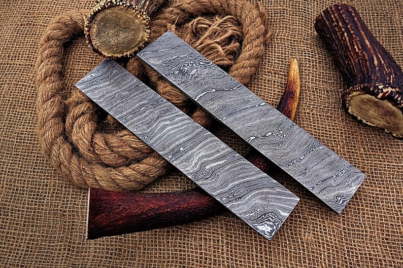 May include: Two long, rectangular pieces of metal with a wavy, patterned surface. The metal is a light gray color. The pieces are lying on a brown burlap surface.