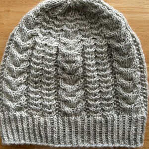 Women&#39;s wool mix hat (Aran weight yarn). Beautiful cable pattern with seed stitches between the cables. Size small.