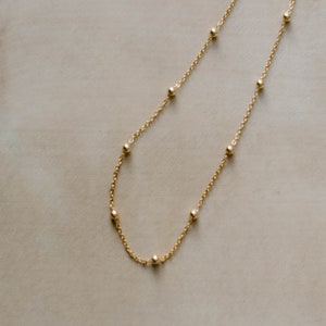 May include: A gold chain necklace with small round beads.