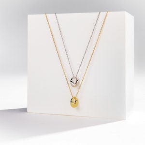 dainty gold circle pendant necklace shown in gold and silver color