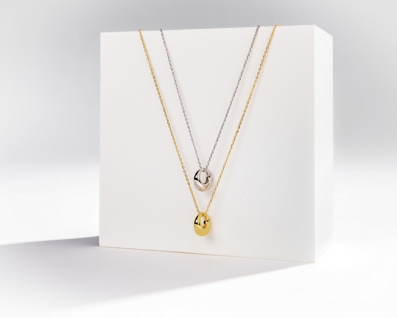 dainty gold circle pendant necklace shown in gold and silver color