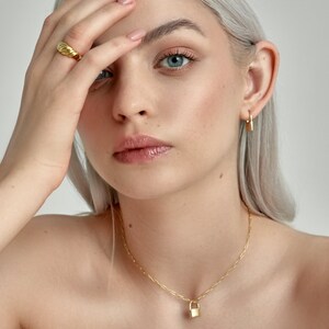 Model is wearing Gold Lock Hoops as an earring and as a padlock charm on a necklace