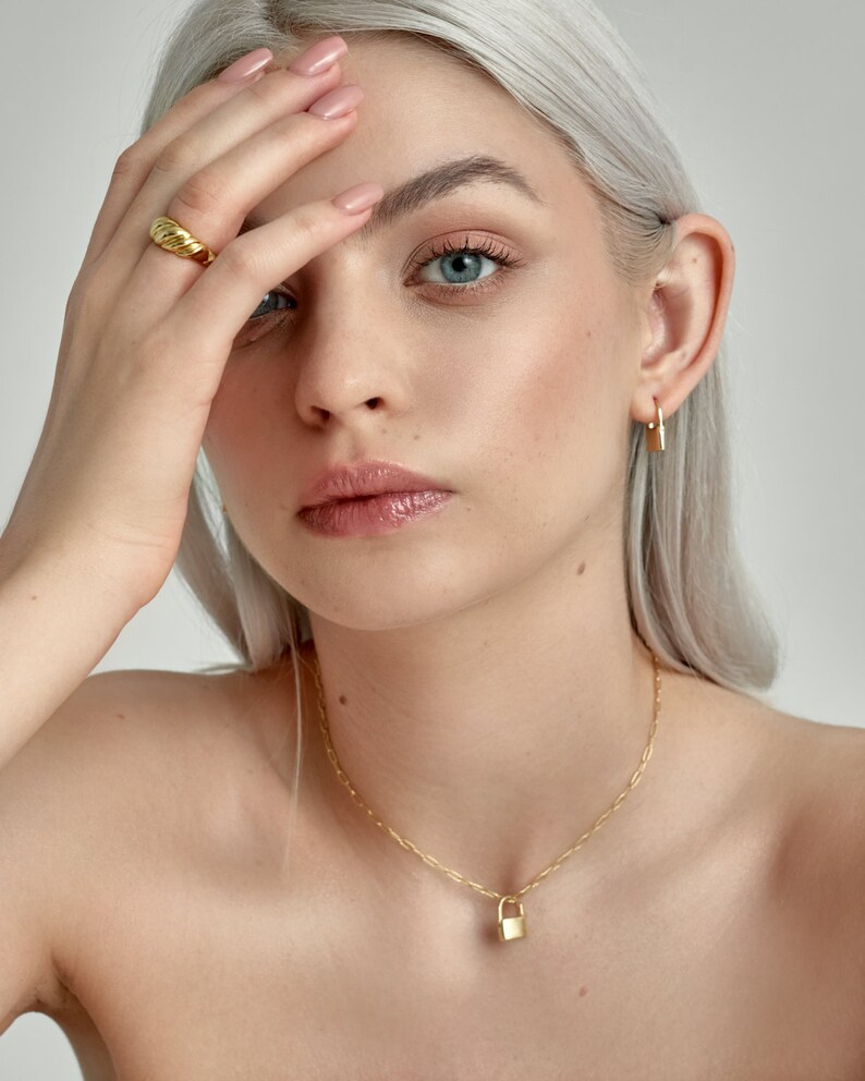 Model is wearing Gold Lock Hoops as an earring and as a padlock charm on a necklace