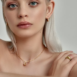 Model is wearing Gold Lock Hoops as an earring and as a padlock charm on a necklace