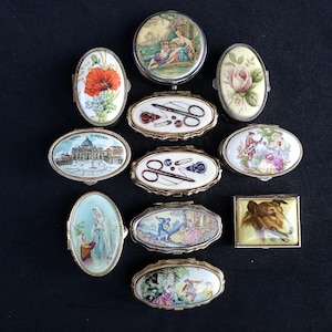 Puede incluir: Una colección de pastilleros y joyeros decorativos antiguos. Las cajas presentan diseños pintados florales, paisajísticos y de retratos. Algunas cajas son ovaladas y otras rectangulares, con marcos metálicos y tapas con bisagras.