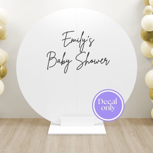 Może przedstawiać: Białe okrągłe tło z czarną naklejką z napisem "Emily's Baby Shower" i fioletowym kółkiem z tekstem "Decal only". Tło stoi na białym stojaku, a po obu stronach znajdują się złote i kremowe balony.