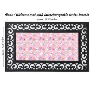 May include: A black doormat with a white border and a pink center insert featuring a repeating pattern of white bunnies and colorful Easter eggs. The mat measures approximately 29.75 inches by 17.5 inches.