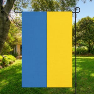 May include: A blue and yellow garden flag. The flag is attached to a black metal pole.