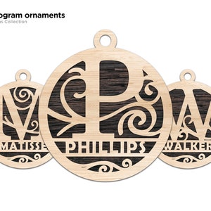 May include: Three wooden Christmas ornaments with a monogram design. The ornaments are round and have a dark wood grain finish. The letters are cut out of the wood and the names "Matisse", "Phillips", and "Walker" are written below the letters.
