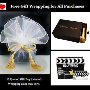 May include: A black gift box with a gold drawer and the text "Hollywood Collection" on the top. The box is wrapped in white tulle with gold ribbon and tassels. The image also shows a black and white clapperboard with the text "HOLLYWOOD" on it.