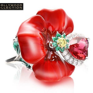 Puede incluir: Anillo en forma de flor roja vibrante con una gran piedra preciosa rosa y piedras verdes y amarillas más pequeñas. El anillo tiene una banda plateada. El anillo es parte de la Colección Hollywood.