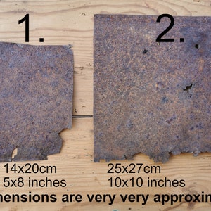 Könnte beinhalten: Zwei rechteckige Platten aus verwittertem, dunkelbraun verrostetem Metall mit unregelmäßigen, gezackten Kanten und einer narbigen Oberfläche. Platte 1 ist mit 14x20cm und Platte 2 mit 25x27cm beschriftet. Der Text weist auf sehr ungefähre Maße hin.