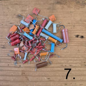K&ouml;nnte beinhalten: Eine Sammlung verschiedener elektronischer Bauteile, darunter diverse Widerst&auml;nde und Kondensatoren in den Farben Rot, Blau, Orange und Grau. Diese kleinen zylindrischen und rechteckigen Teile haben d&uuml;nne Metalldrahtanschl&uuml;sse.