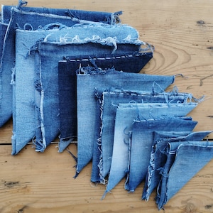 Könnte beinhalten: Eine Sammlung von Jeansstoffresten in verschiedenen Blautönen, die in einem dreieckigen Muster auf einer Holzoberfläche angeordnet sind.
