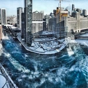 May include: An aerial view of a city skyline with a river flowing through it. The river is frozen over and there is steam rising from the water. The buildings are tall and modern, and there are several bridges crossing the river.