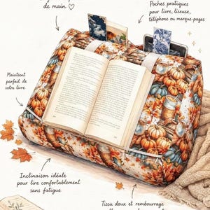 K&ouml;nnte beinhalten: Ein keilf&ouml;rmiges Lesekissen mit herbstlichem Druck von K&uuml;rbissen, Bl&auml;ttern und Tassen. Das Kissen hat eine Kante zum Halten eines offenen Buches und R&uuml;ckentaschen. Text auf dem Bild: Vos lectures toujours &agrave; port&eacute;e de main, Poches pratiques pour livre, liseuse, t&eacute;l&eacute;phone ou marque-pages, Maintient parfait de votre livre, Inclinaison id&eacute;ale pour lire confortablement sans fatigue, Tissu doux et rembourrage moelleux pour des moments de lecture tout en douceur.