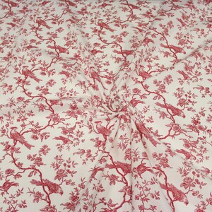 K&ouml;nnte beinhalten: Ein cremefarbener Stoff mit einem sich wiederholenden roten Toile-Muster. Das Design zeigt detaillierte Illustrationen von V&ouml;geln, die auf bl&uuml;henden Zweigen mit Bl&auml;ttern und Bl&uuml;ten sitzen und ein durchgehendes botanisches und vogelartiges Motiv bilden.
