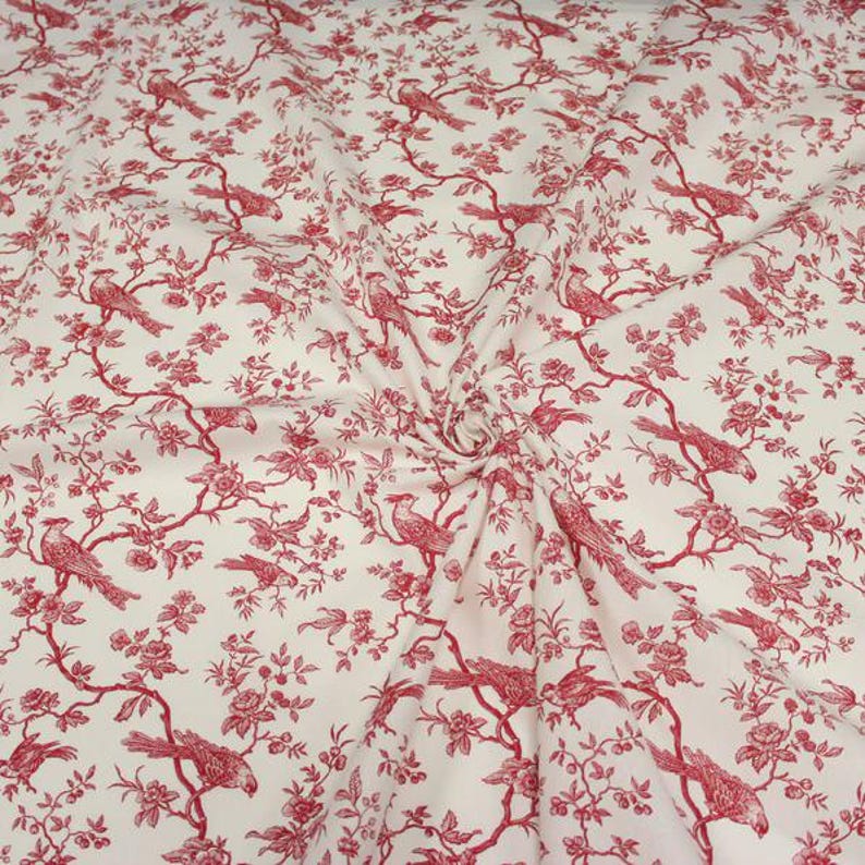 K&ouml;nnte beinhalten: Ein cremefarbener Stoff mit einem sich wiederholenden roten Toile-Muster. Das Design zeigt detaillierte Illustrationen von V&ouml;geln, die auf bl&uuml;henden Zweigen mit Bl&auml;ttern und Bl&uuml;ten sitzen und ein durchgehendes botanisches und vogelartiges Motiv bilden.