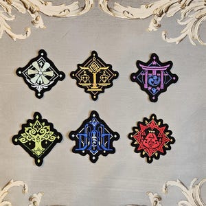 May include: Six embroidered iron-on patches in various colours and designs. The patches feature geometric shapes, symbols, and patterns.