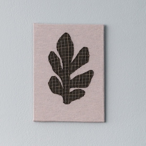 May include: A black and white leaf-shaped design on a pink canvas.