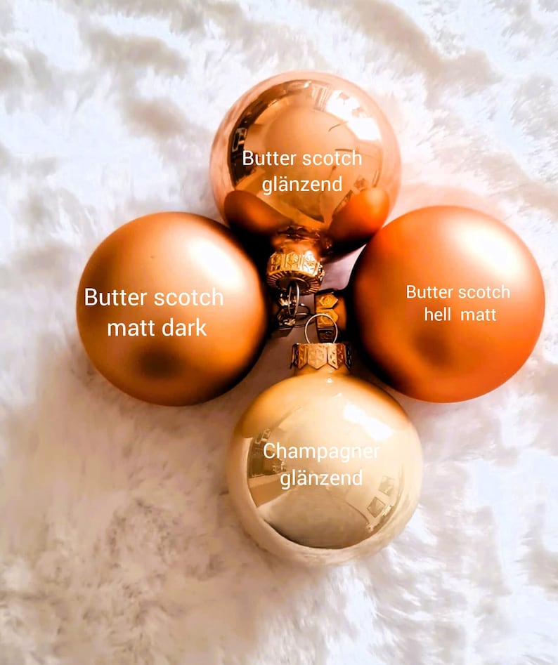 Pu&ograve; includere: Quattro ornamenti natalizi nei toni dell'oro e del bronzo. Gli ornamenti includono un butterscotch lucido, un butterscotch opaco scuro, un butterscotch opaco chiaro e un ornamento color champagne lucido. Il testo sugli ornamenti recita "Butter scotch gl&auml;nzend", "Butter scotch matt dark", "Butter scotch hell matt" e "Champagner gl&auml;nzend".