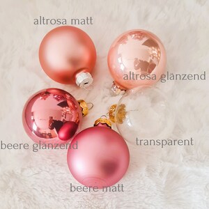 Pu&ograve; includere: Un assortimento di palline di Natale in varie tonalit&agrave; di rosa e vetro trasparente. Le palline hanno finiture opache e lucide. Il testo sull'immagine indica i nomi dei colori: "altrosa matt", "altrosa gl&auml;nzend", "beere gl&auml;nzend", "beere matt" e "transparent".