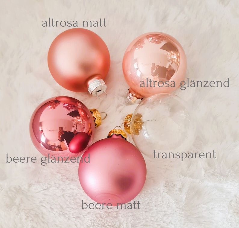 Pu&ograve; includere: Un assortimento di palline di Natale in varie tonalit&agrave; di rosa e vetro trasparente. Le palline hanno finiture opache e lucide. Il testo sull'immagine indica i nomi dei colori: "altrosa matt", "altrosa gl&auml;nzend", "beere gl&auml;nzend", "beere matt" e "transparent".