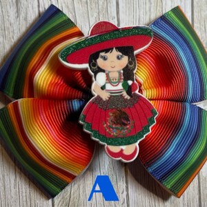 May include: A colorful rainbow striped hair bow with a girl wearing a red, green, and white dress and a sombrero. The girl is holding a small Mexican flag.