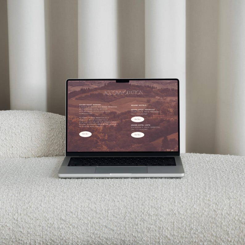 May include: A silver laptop displaying a website with the word "ACCOMMODATION" at the top. The website features text and images of hotels. The laptop is open on a white, textured surface.