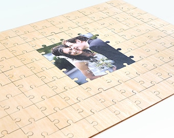 May include: A wooden jigsaw puzzle with a photo of a couple in the centre. The puzzle is made of light wood and has a natural finish.