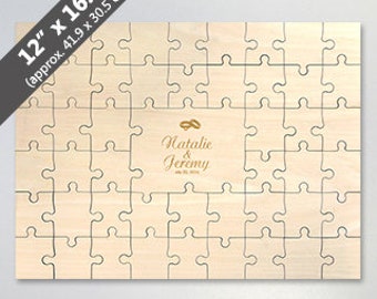 May include: A wooden jigsaw puzzle with a white background and a small rectangular frame in the centre. The frame contains the text "Natalie & Jeremy" in a gold script font with two gold rings above the text. The puzzle is 12 inches by 16.5 inches, or approximately 41.9 centimetres by 30.5 centimetres.