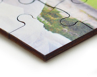 May include: Close-up of a wooden jigsaw puzzle piece with a colourful image of a landscape. The piece is partially assembled with other pieces.