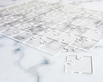 May include: A white acrylic jigsaw puzzle with one piece missing. The puzzle is on a white marble surface.
