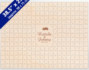 May include: A personalised 38.5" x 29.5" (98 x 75 cm) wooden jigsaw puzzle with the names "Natalie & Jeremy" and the date "July 23, 2016" printed on it. The puzzle features two gold rings above the names.