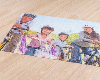 May include: A family of four cycling outdoors. The father is wearing a blue helmet and a blue shirt. The mother is wearing a white helmet and a grey shirt. The two children are wearing helmets and colourful shirts. The bicycles are all different colours.