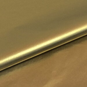 May include: A close-up of a smooth, gold fabric with a subtle sheen. The fabric is folded in half, creating a diagonal line.