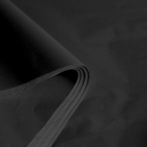 May include: Black tissue paper, folded in a stack, showing the texture and colour of the paper.