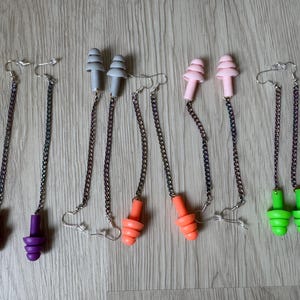 May include: Six pairs of earplugs with chains. The earplugs are in various colors, including purple, orange, pink, and green. The chains are silver.
