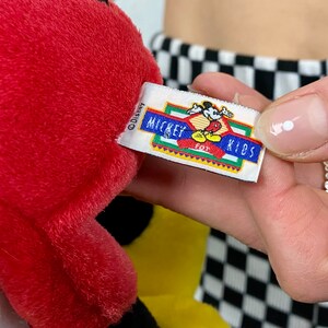 May include: Red and black plush Mickey Mouse toy with a yellow tag that reads "Disney Mickey for Kids".