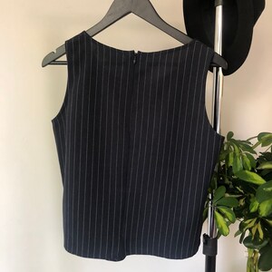 Puede incluir: Una blusa sin mangas de rayas blancas y negras con cierre de cremallera en la espalda.