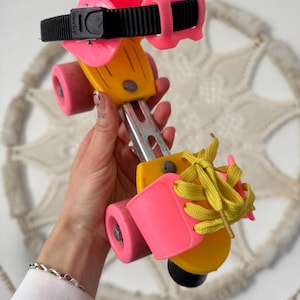 May include: A pair of vintage roller skates in bright colors. The skates feature a yellow base, pink accents, and pink wheels. The laces are yellow, and the adjustable strap is black. The skates are designed for recreational use.