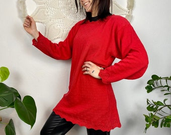 May include: A red long-sleeved sweater with a scalloped hem and a textured knit. The sweater is loose-fitting and has a relaxed silhouette.