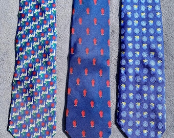 May include: Three neckties with different patterns. One tie has a repeating pattern of red and white shapes on a blue background. Another tie has a pattern of red shapes on a blue background. The third tie has a pattern of blue and yellow circles on a blue background.