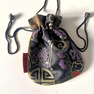May include: A small black drawstring bag with gold and purple floral embroidery. The bag has a red label with the word "MissLily" on it.