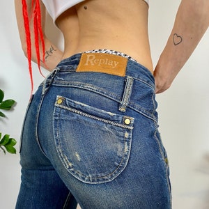 May include: A pair of blue denim jeans with a brown leather patch that says "Replay" on the back pocket.