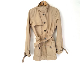 May include: A beige trench coat with a belt and pockets. The coat has a button closure and a collar.