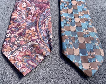 May include: Two neckties are displayed. One tie features a paisley design in shades of purple, orange, and pink. The other tie has a geometric pattern in blue and brown squares. Both ties are on a gray surface.